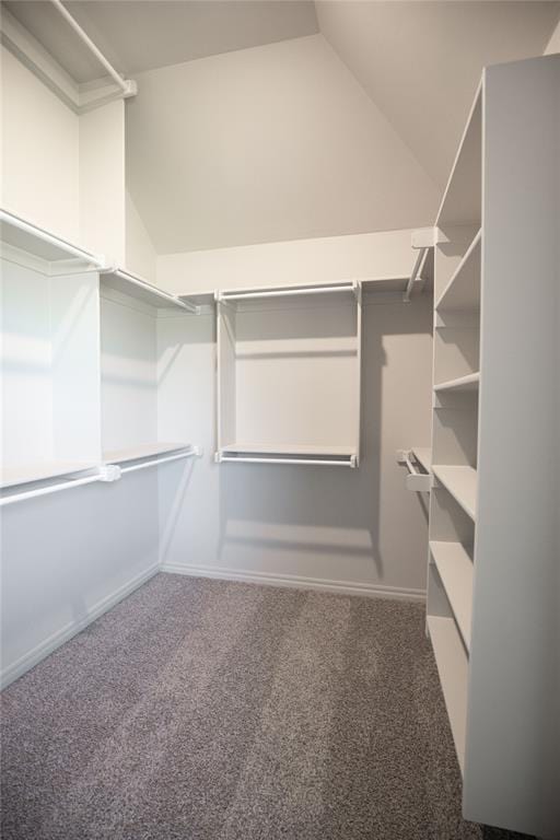 spacious closet with dark colored carpet and vaulted ceiling