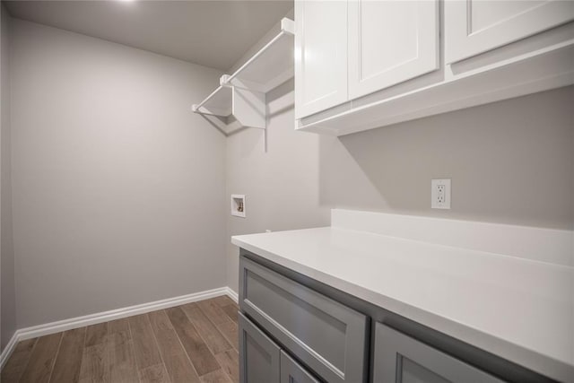 clothes washing area with cabinets, washer hookup, and dark wood-type flooring