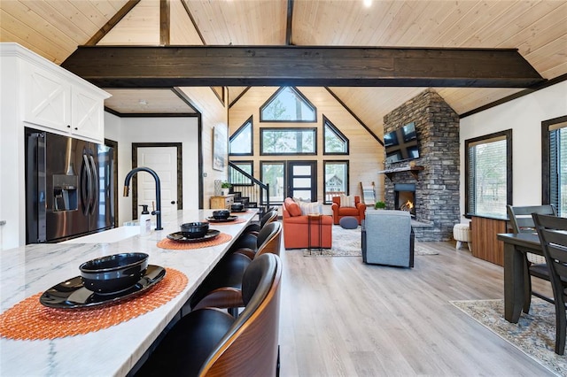 kitchen featuring beamed ceiling, plenty of natural light, white cabinets, and stainless steel fridge with ice dispenser