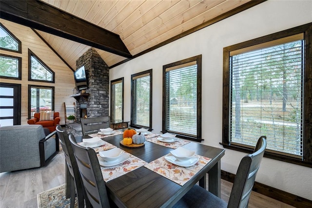 dining room with vaulted ceiling with beams, hardwood / wood-style flooring, plenty of natural light, and wood ceiling