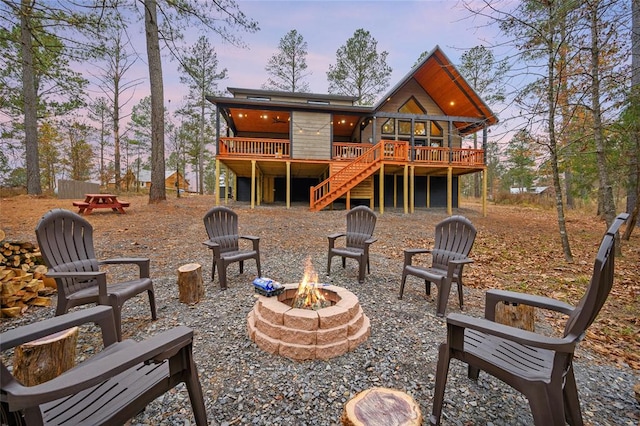 back house at dusk with a deck and an outdoor fire pit