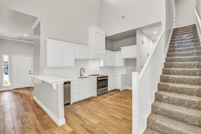 kitchen with white cabinetry, sink, stainless steel appliances, and light wood-type flooring