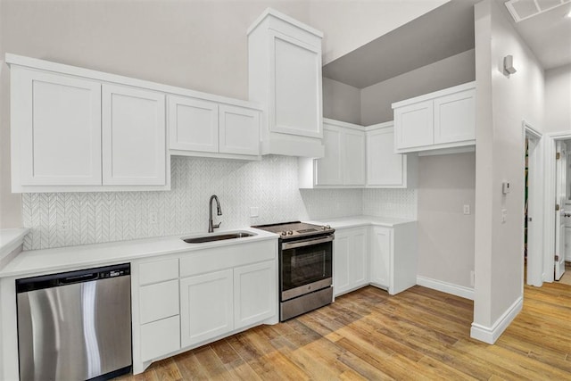 kitchen with white cabinetry, sink, tasteful backsplash, appliances with stainless steel finishes, and light wood-type flooring