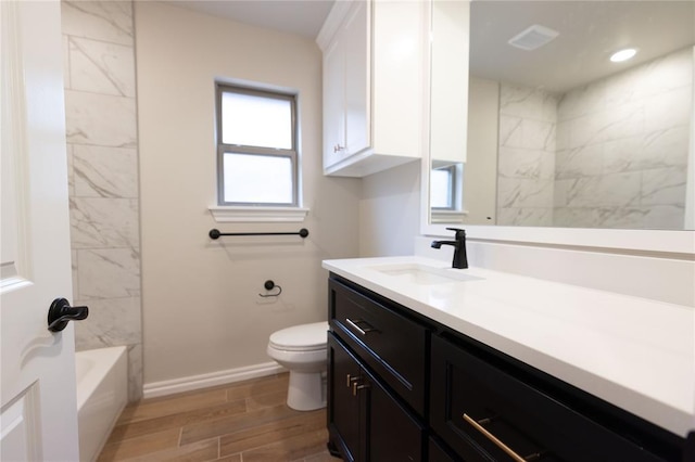 full bathroom featuring vanity, tiled shower / bath, plenty of natural light, and toilet