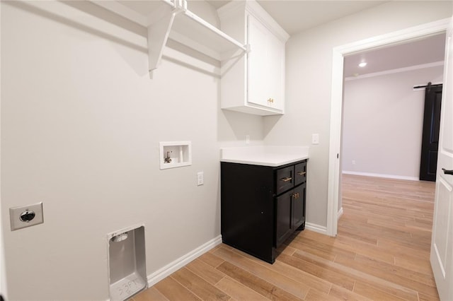 clothes washing area with cabinets, light wood-type flooring, hookup for a washing machine, electric dryer hookup, and a barn door