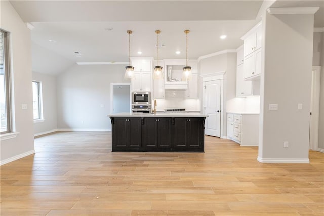 kitchen with appliances with stainless steel finishes, pendant lighting, white cabinets, a kitchen island with sink, and light hardwood / wood-style floors