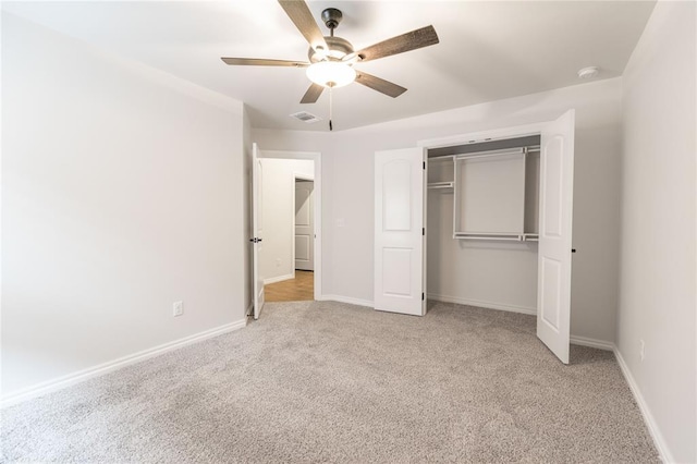 unfurnished bedroom featuring ceiling fan, light colored carpet, and a closet