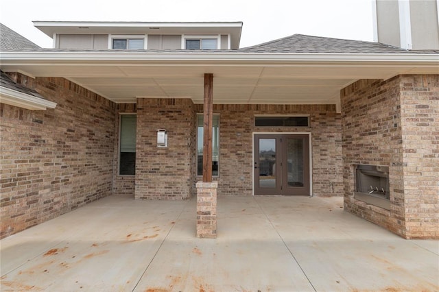 view of patio with an outdoor brick fireplace and french doors