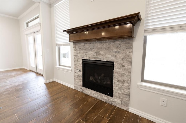 details featuring wood-type flooring, a stone fireplace, and ornamental molding