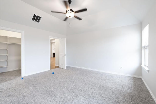 unfurnished bedroom featuring carpet, a spacious closet, lofted ceiling, and a closet