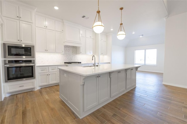 kitchen with visible vents, backsplash, stainless steel oven, a sink, and built in microwave