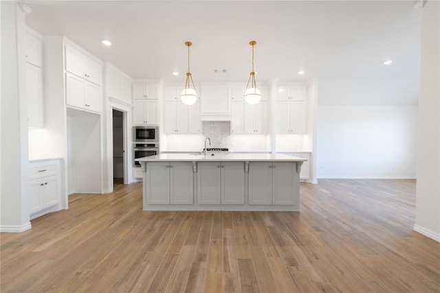 kitchen with stainless steel appliances, backsplash, light countertops, and white cabinetry