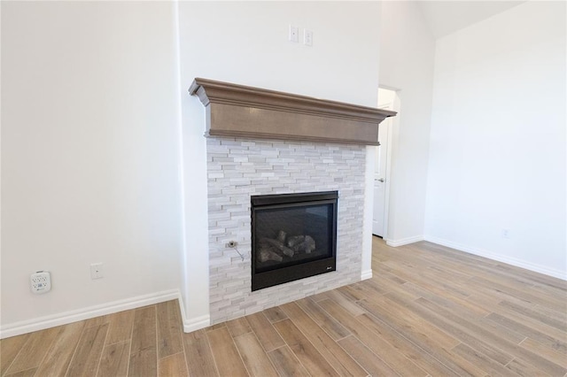 room details with baseboards, wood finished floors, and a stone fireplace