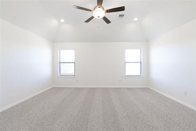 carpeted spare room featuring baseboards, vaulted ceiling, and a wealth of natural light