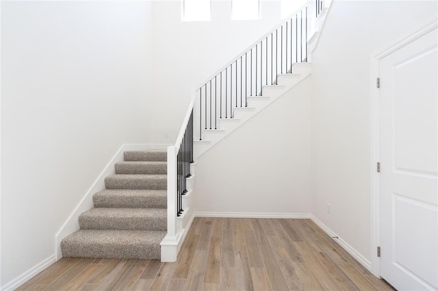 staircase featuring wood finished floors and baseboards