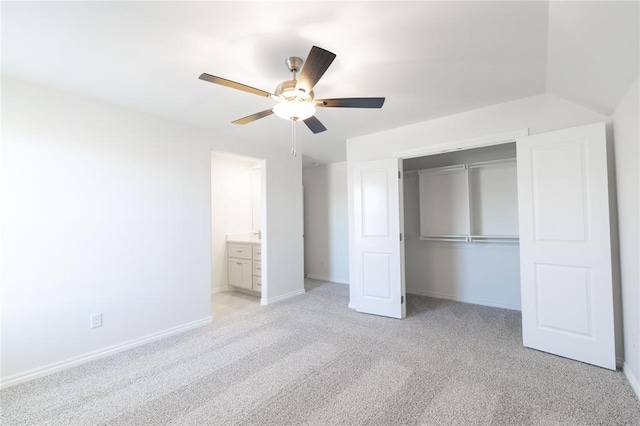 unfurnished bedroom featuring light carpet, baseboards, a ceiling fan, ensuite bath, and a closet