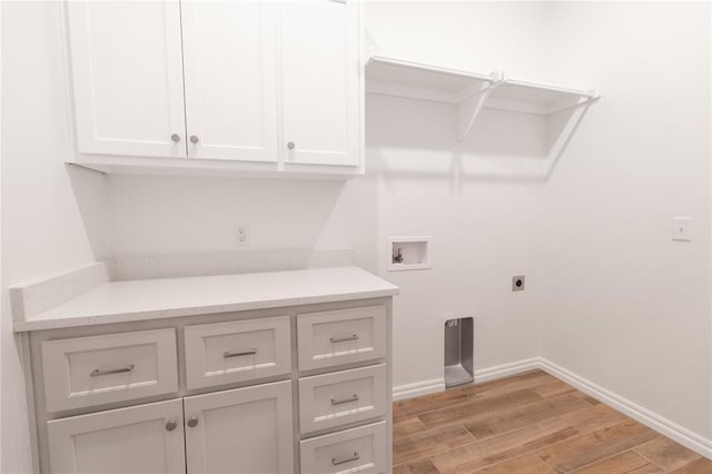 laundry room featuring cabinet space, baseboards, light wood-style flooring, hookup for a washing machine, and hookup for an electric dryer