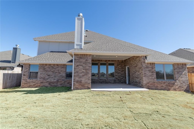 back of property featuring brick siding, a patio area, fence, and roof with shingles