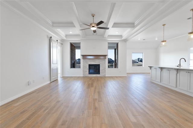 unfurnished living room featuring a barn door, light hardwood / wood-style floors, crown molding, and coffered ceiling