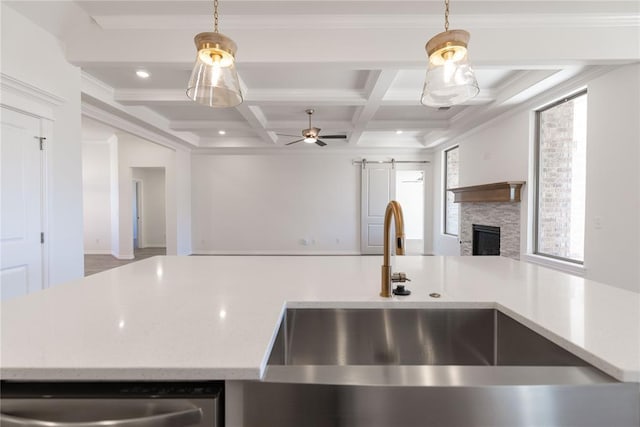 kitchen featuring coffered ceiling, sink, a barn door, decorative light fixtures, and beamed ceiling