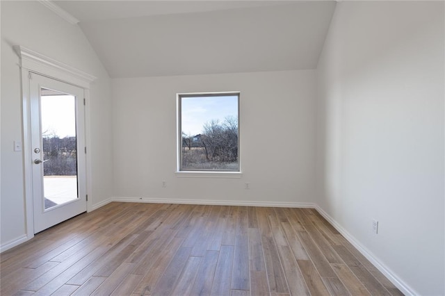 unfurnished room featuring lofted ceiling, light wood-type flooring, and a healthy amount of sunlight