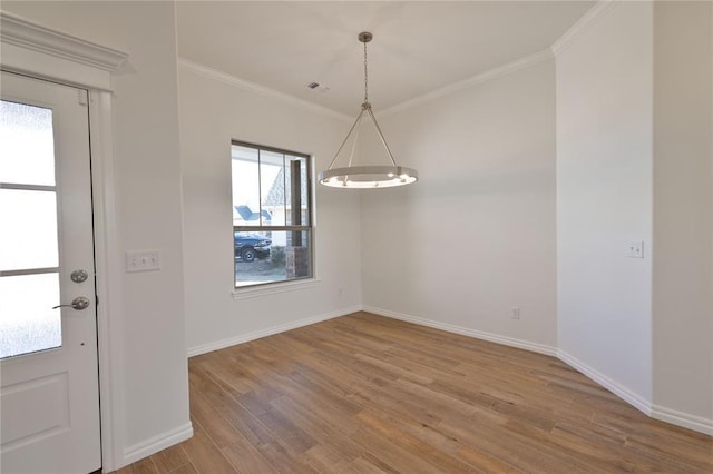 unfurnished dining area with hardwood / wood-style floors, a healthy amount of sunlight, crown molding, and an inviting chandelier