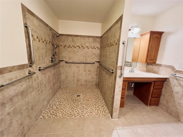 bathroom with tiled shower, vanity, tile patterned floors, and tile walls