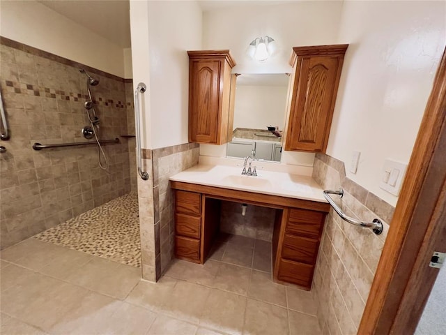 bathroom with tile patterned floors, vanity, a tile shower, and tile walls