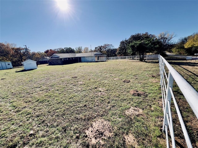 view of yard featuring a rural view and a storage unit