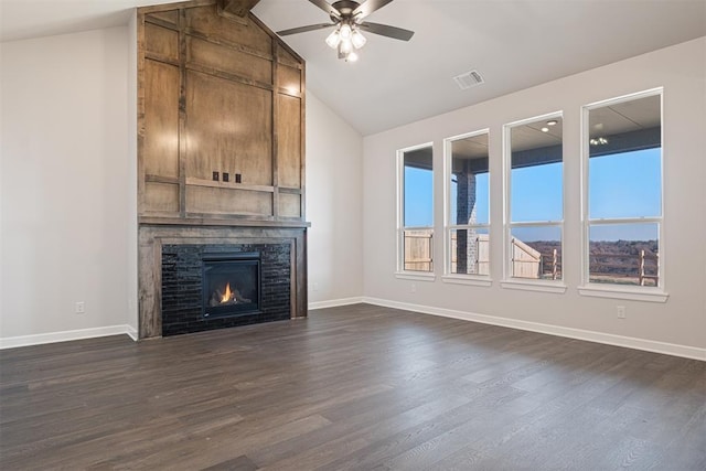 unfurnished living room with dark hardwood / wood-style flooring, lofted ceiling with beams, a stone fireplace, and a healthy amount of sunlight