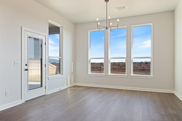 unfurnished dining area featuring dark hardwood / wood-style floors and an inviting chandelier