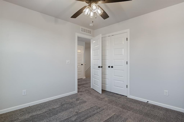 unfurnished bedroom with dark colored carpet, ceiling fan, and a closet