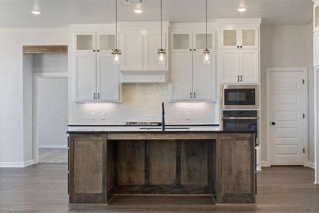 13268 Sawtooth Oak Rd, Choctaw, OK 73020 - kitchen featuring built in microwave, oven, a center island with sink, tasteful backsplash, and white cabinetry