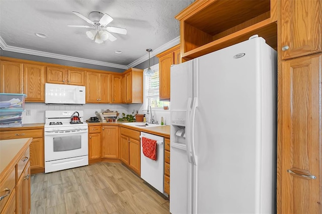 kitchen with ornamental molding, white appliances, sink, pendant lighting, and light hardwood / wood-style floors