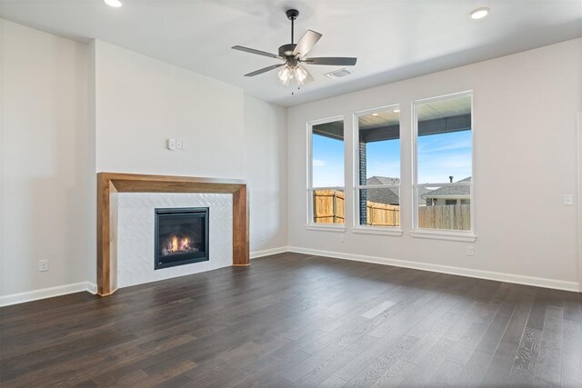 unfurnished living room with a high end fireplace, ceiling fan, and dark wood-type flooring