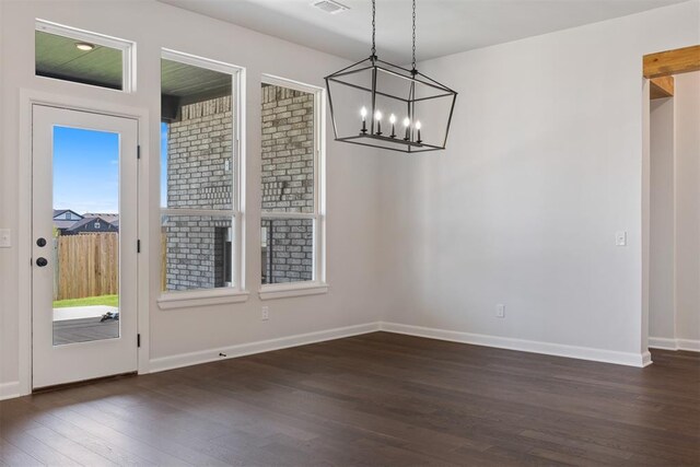 unfurnished dining area with a chandelier and dark hardwood / wood-style floors