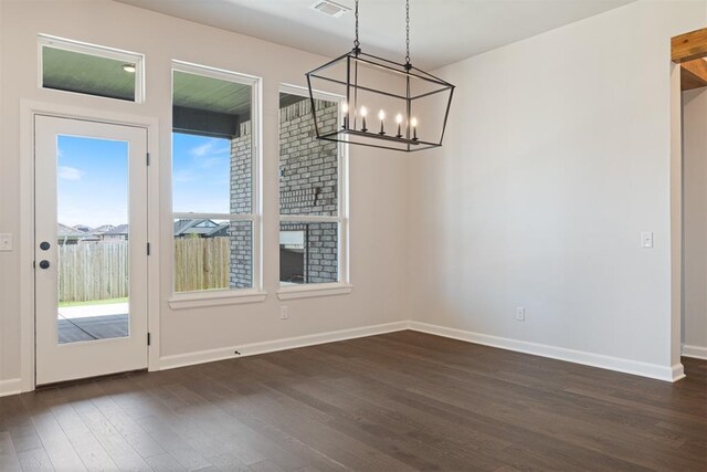 unfurnished dining area with a fireplace, dark wood-type flooring, and a chandelier