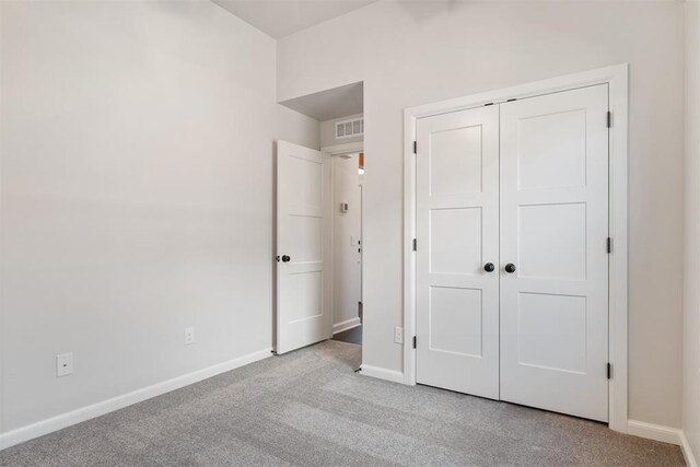 unfurnished bedroom featuring light colored carpet and a closet