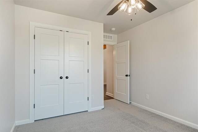 unfurnished bedroom featuring a closet, ceiling fan, and light colored carpet