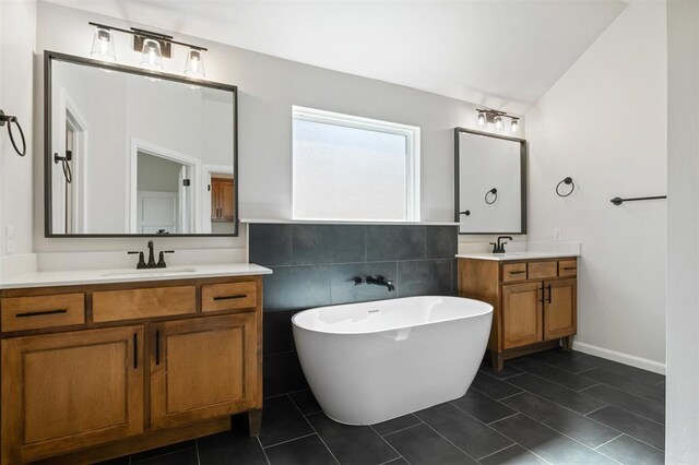 bathroom with a washtub, vanity, and tile patterned flooring