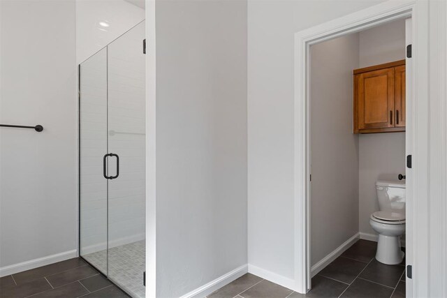 bathroom with tile patterned flooring, toilet, and an enclosed shower