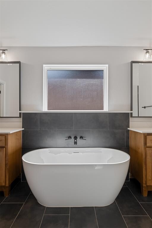 bathroom with tile patterned flooring, vanity, tile walls, and a washtub