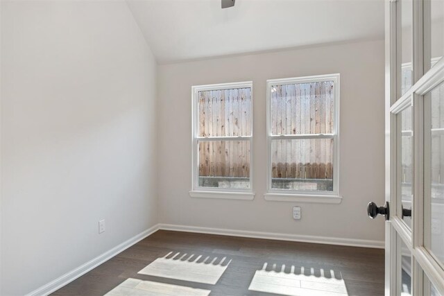 spare room featuring vaulted ceiling and dark hardwood / wood-style floors