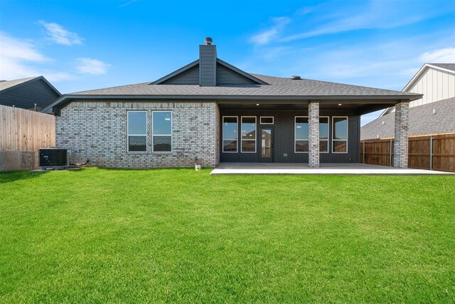 rear view of property featuring a yard, cooling unit, and a patio