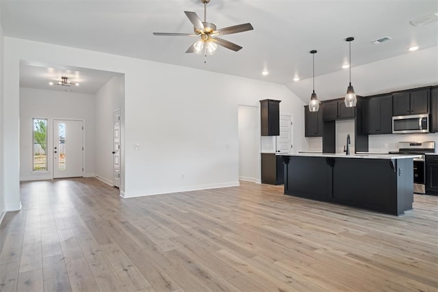 kitchen with a kitchen island with sink, light hardwood / wood-style flooring, ceiling fan, and appliances with stainless steel finishes