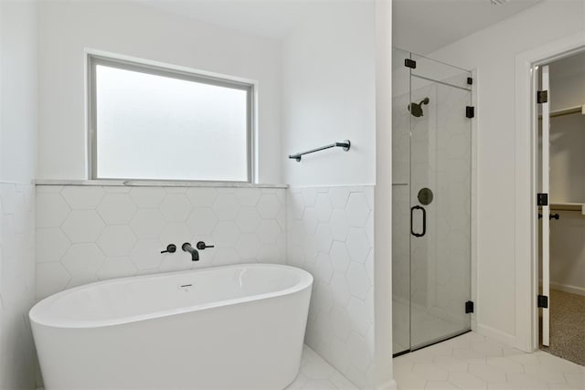 bathroom featuring shower with separate bathtub, tile patterned floors, and tile walls