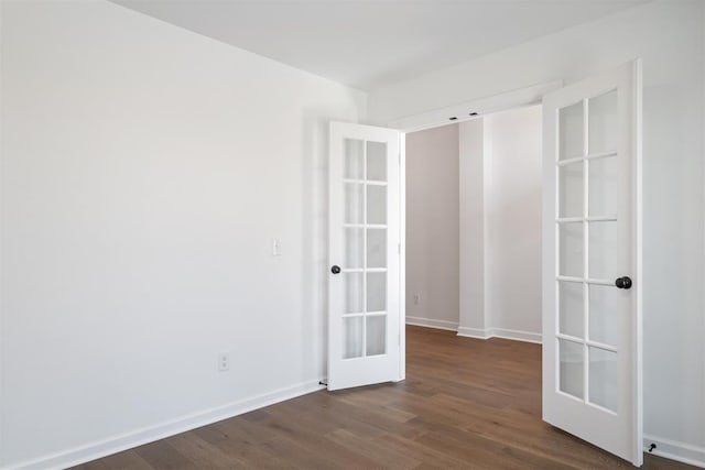 spare room featuring french doors and dark wood-type flooring