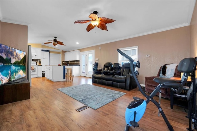 living room featuring ceiling fan, vaulted ceiling, crown molding, and light hardwood / wood-style flooring