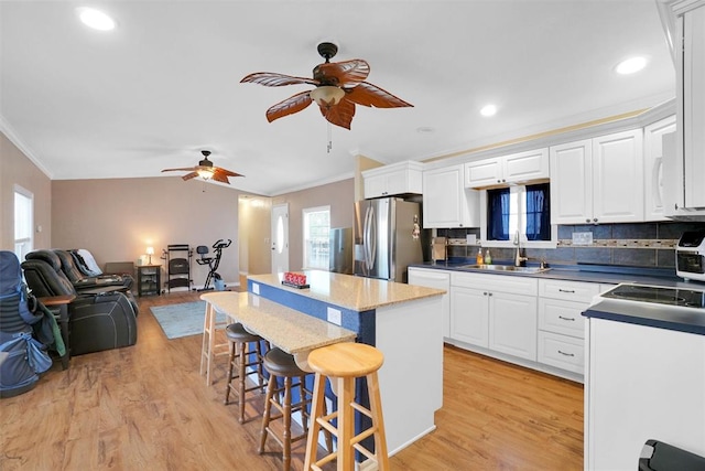 kitchen featuring white cabinetry, sink, a kitchen breakfast bar, stainless steel fridge with ice dispenser, and light wood-type flooring