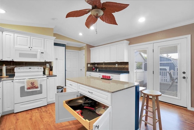 kitchen featuring lofted ceiling, white appliances, white cabinets, decorative backsplash, and a kitchen island